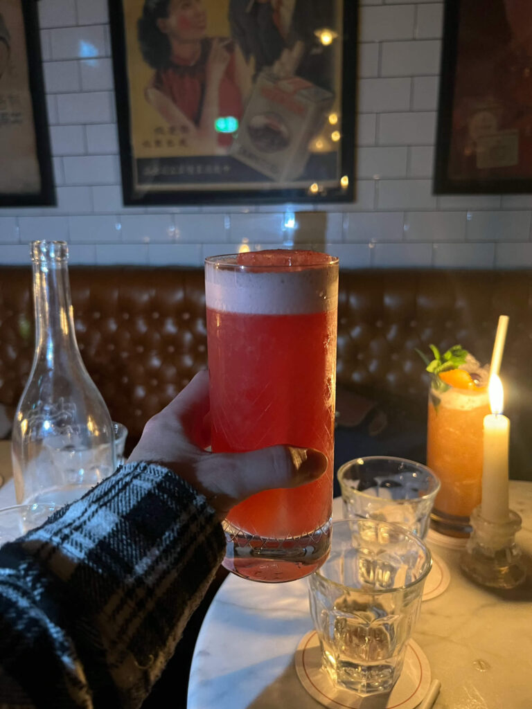 A hand holds out a cocktail glass at the Vintage Cocktail Club, a speakeasy in Dublin.
