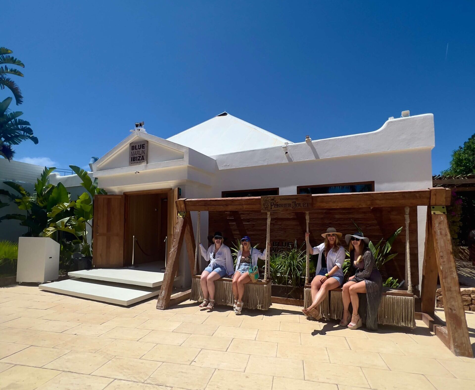 Four girls sat on a swing outside Blue Marlin beach club in Ibiza.