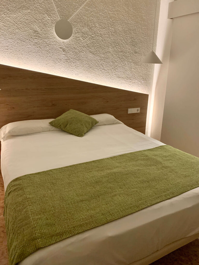 Double bed with green accents at Apuntadores Hostal