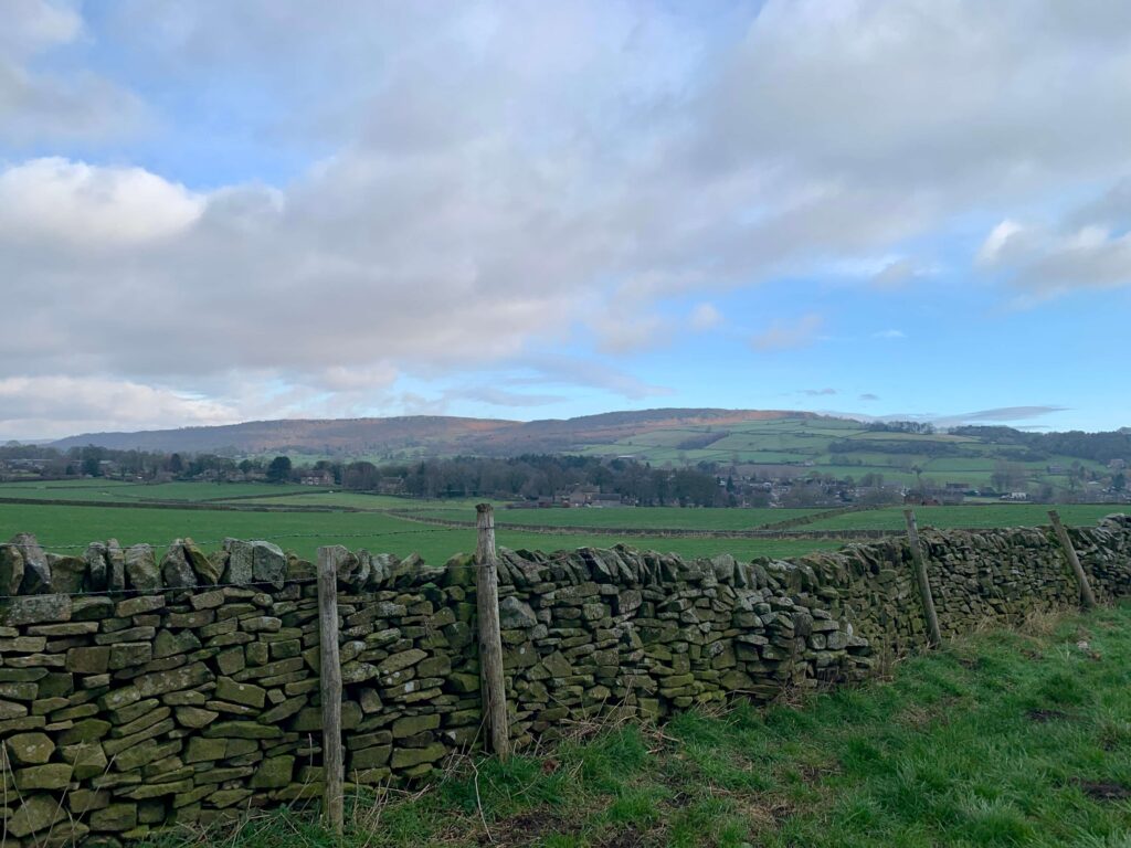 Views of fields and hills in the distance behind a stone wall