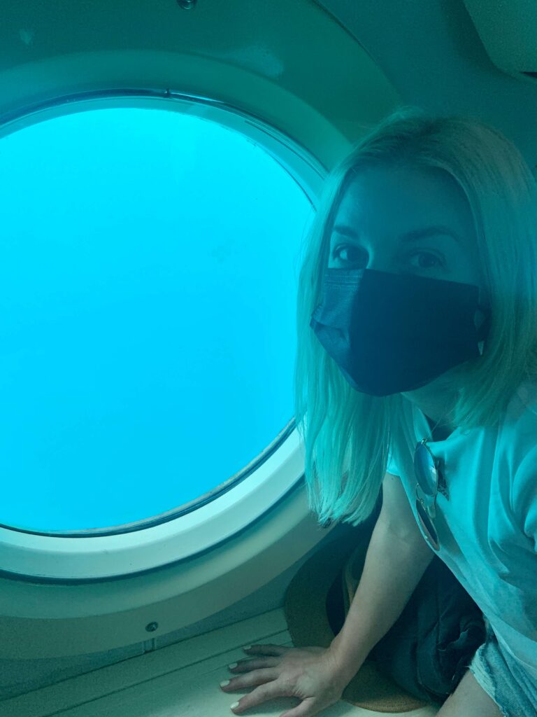 Woman sitting in front of a porthole on a submarine wearing a mask