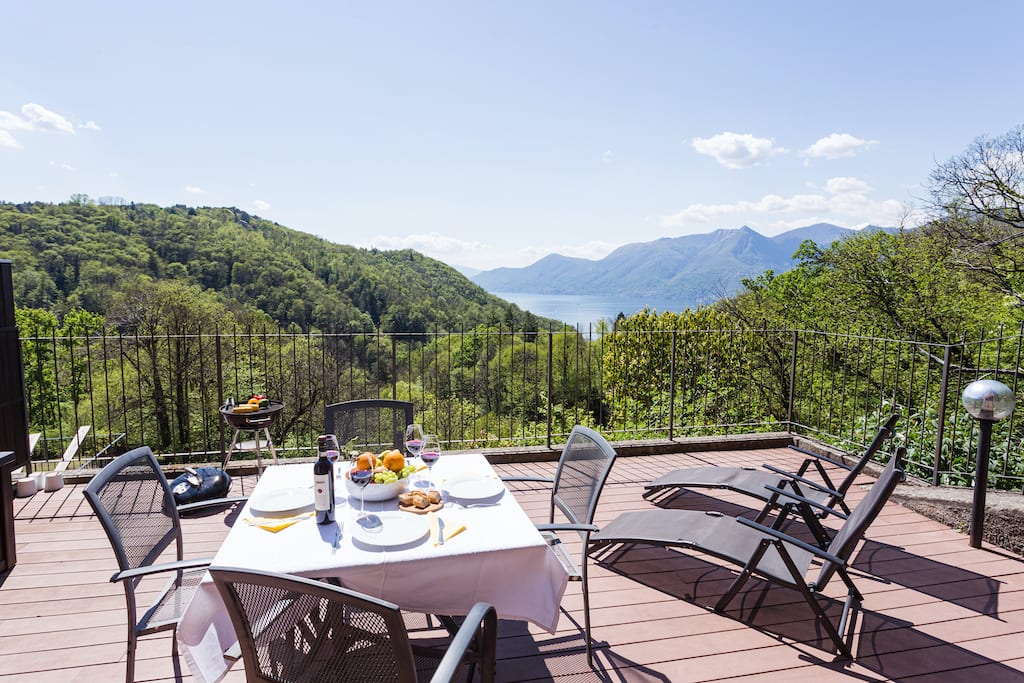 Terrace overlooking Lake Maggiore with a table and chairs and two sun loungers