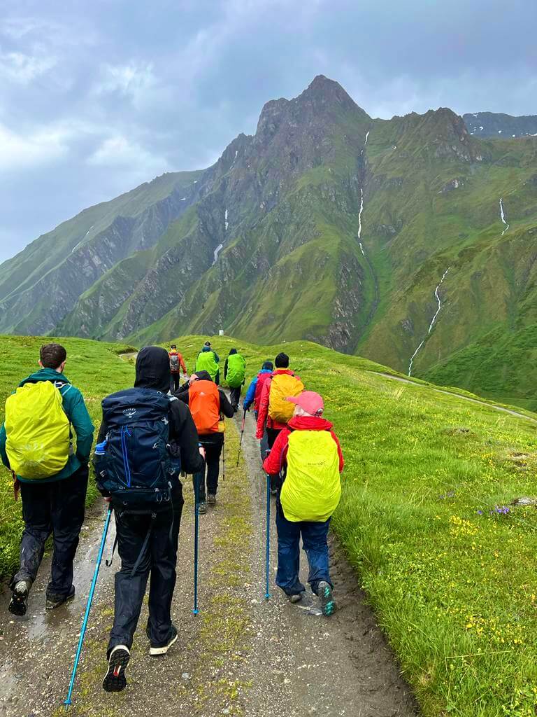 Group of people wearing waterproofs walking in front of a mountain
