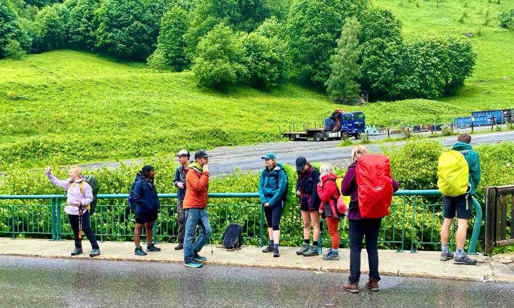 Group of hikers waiting at the side of the road for a bus