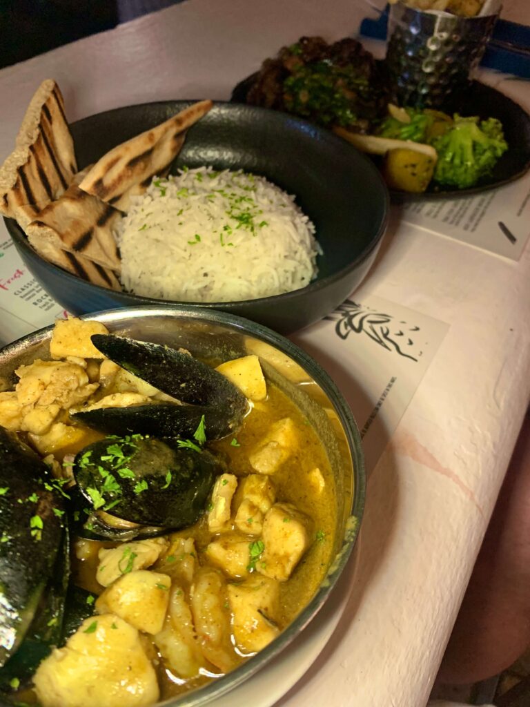 Seafood curry with separate bowl of rice and naan bread