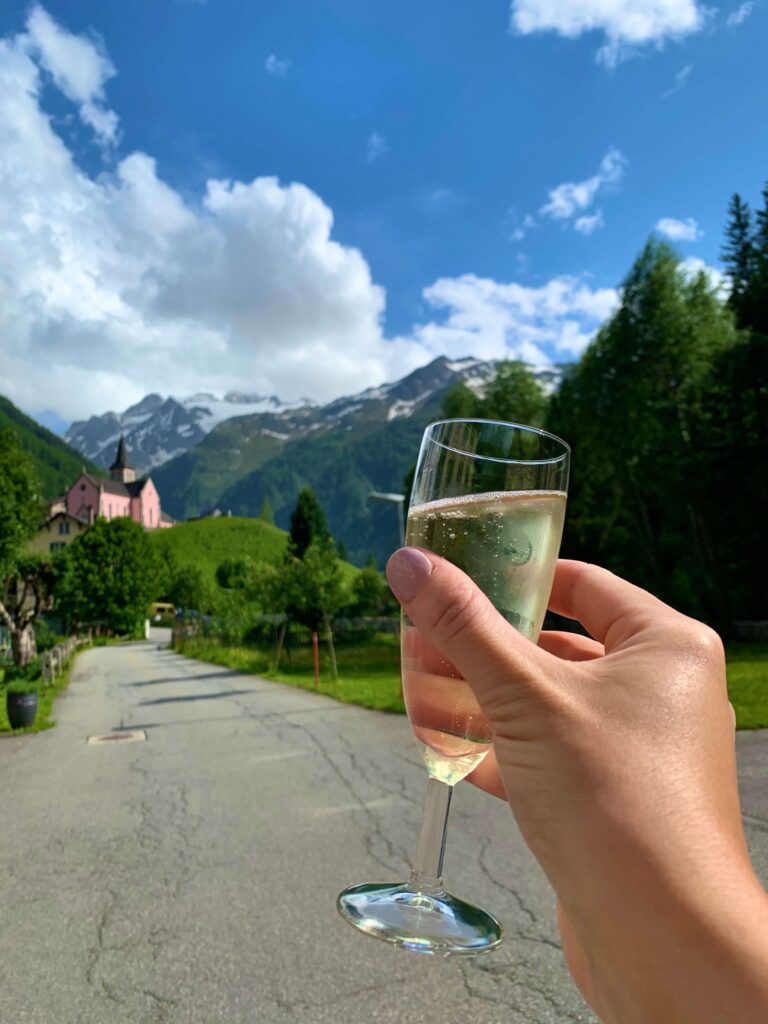 A glass of prosecco being held in front of a mountain view