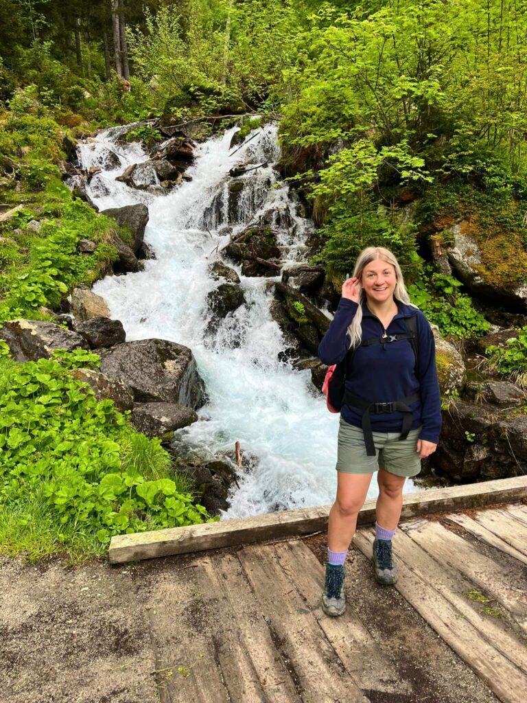 Woman wearing a fleece and shorts standing in front of a waterfall