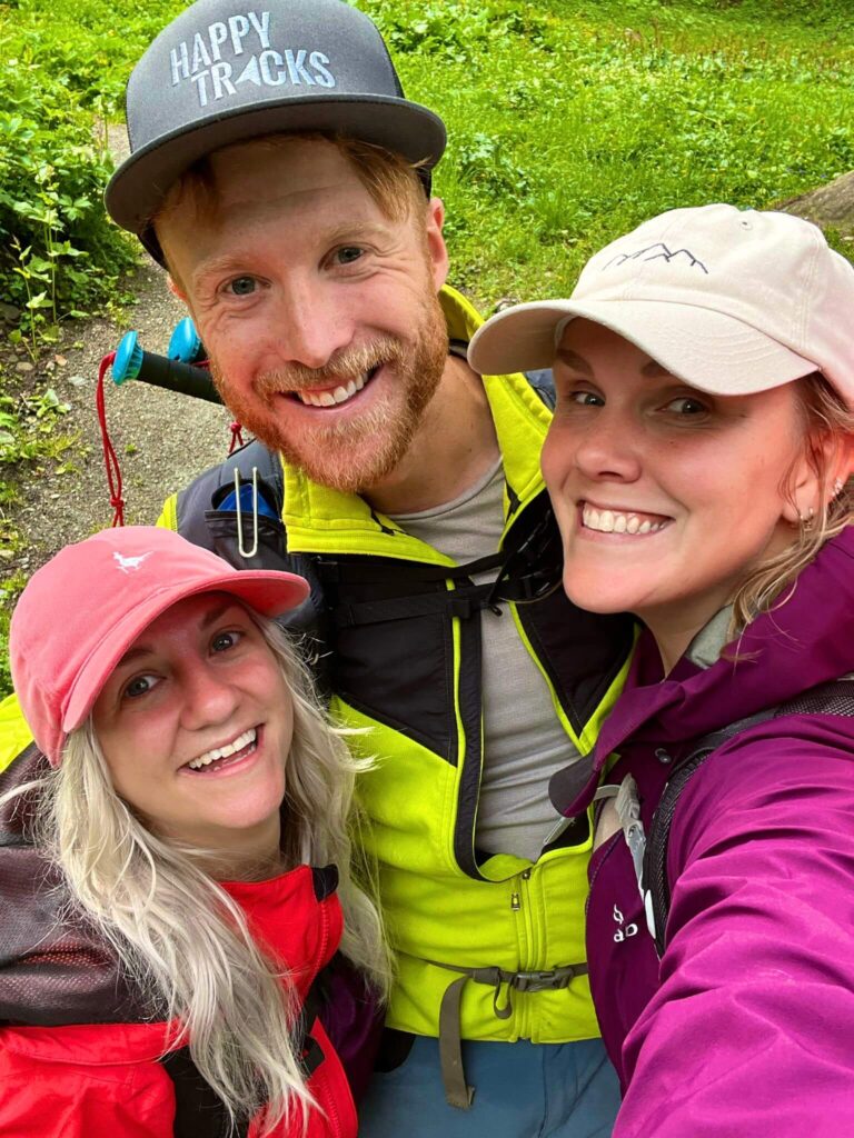 Two women and a man wearing caps taking a selfie