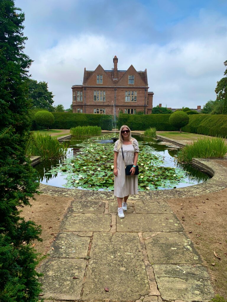 Woman standing in front of a lily pond with Horwood House in the background