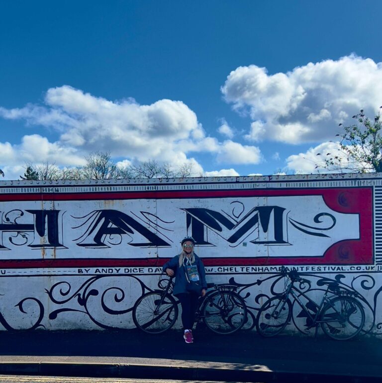 Sam standing in front of the Cheltenham sign in the town.