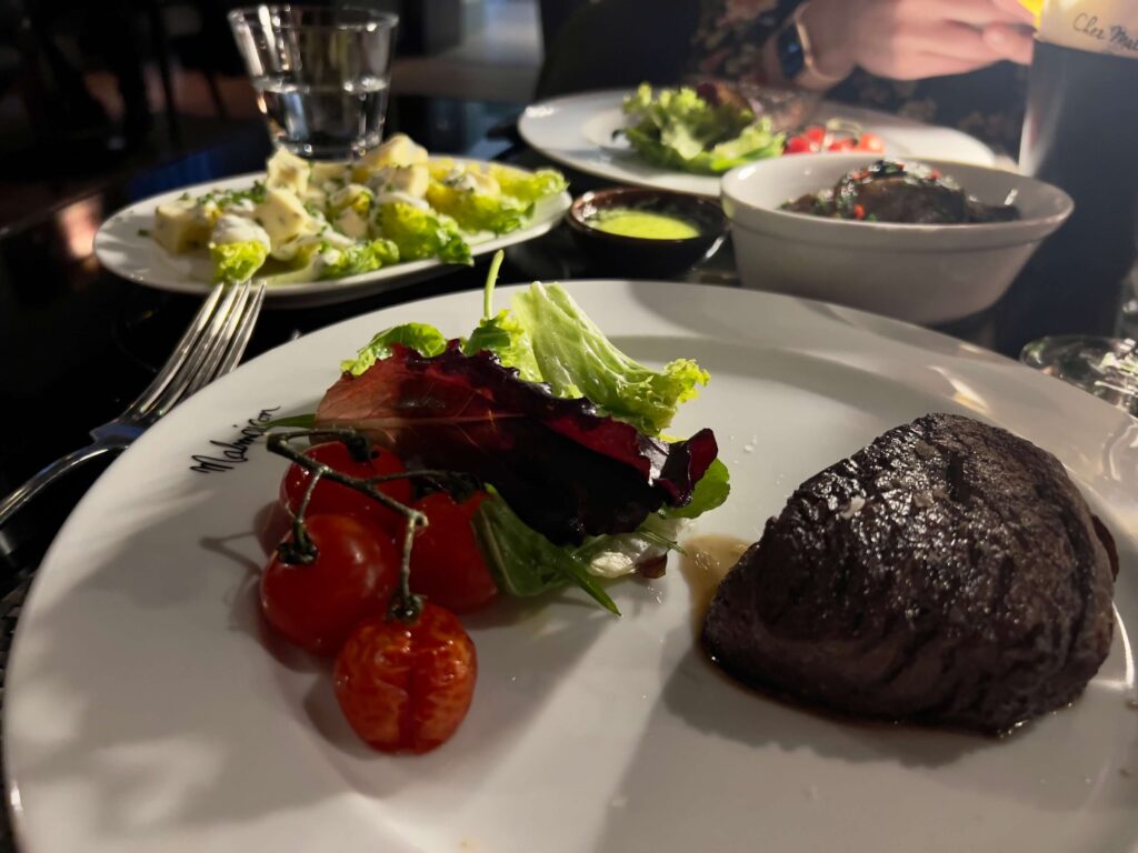 Fillet steak with vine tomatoes and little gem lettuce hearts in the background.