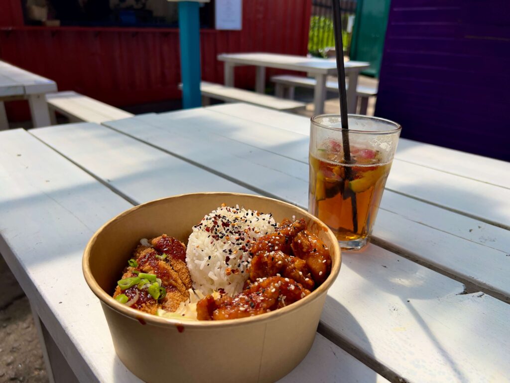 A Korean rice bowl and a glass of Pimm's on a picnic table.