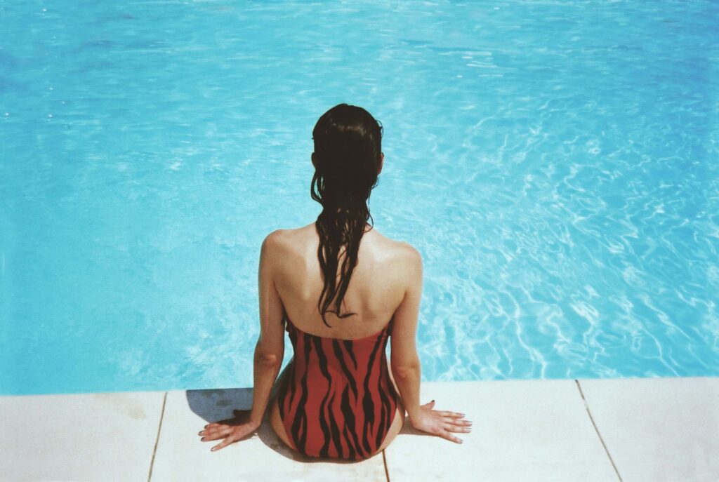Woman sat on the side of a swimming pool.