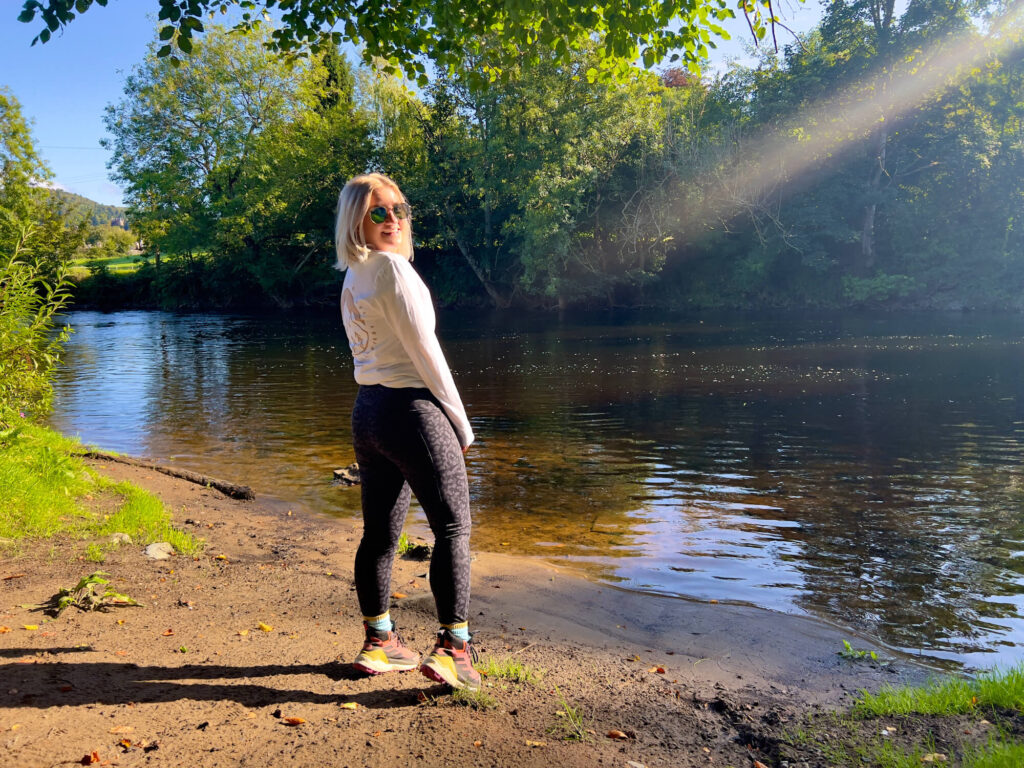 Sam standing in front of a river wearing My Urban Trail leggings.