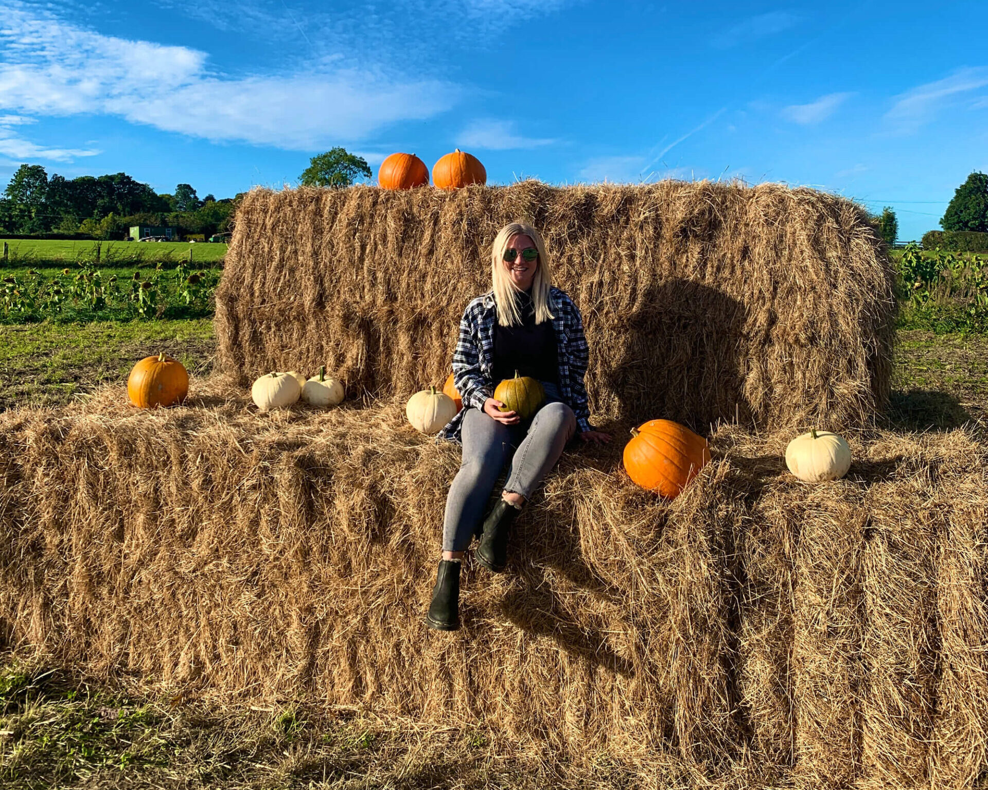 Sam sitting on a hay bale at a pumpkin farm.