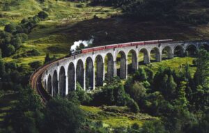 A steam train travels over Glen Finnan Viaduct in Scotland.