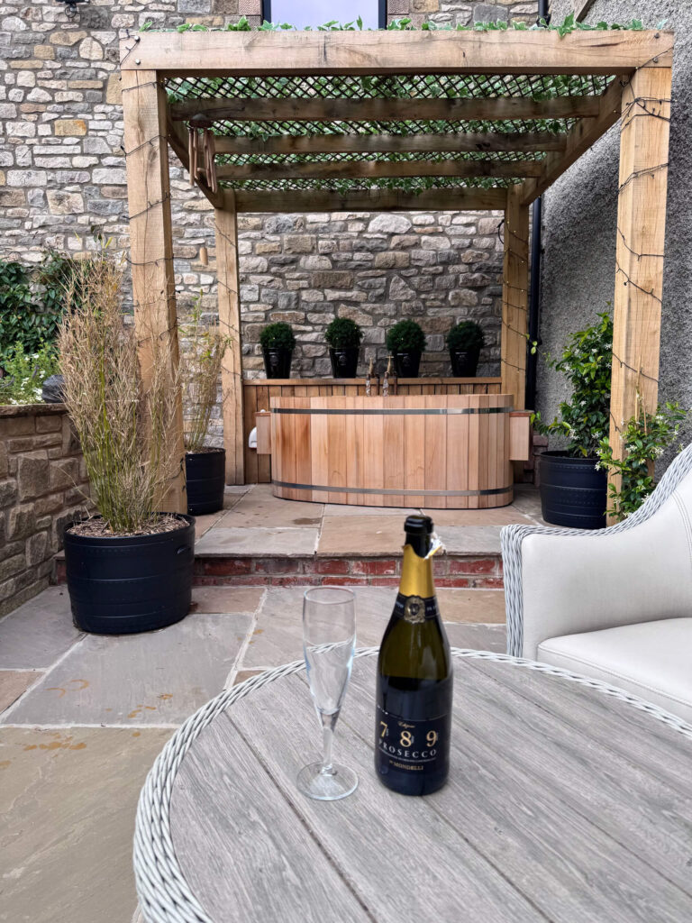 A bottle of prosecco in front of the outdoor bathtub at Westhills Courtyard in the Peak District.