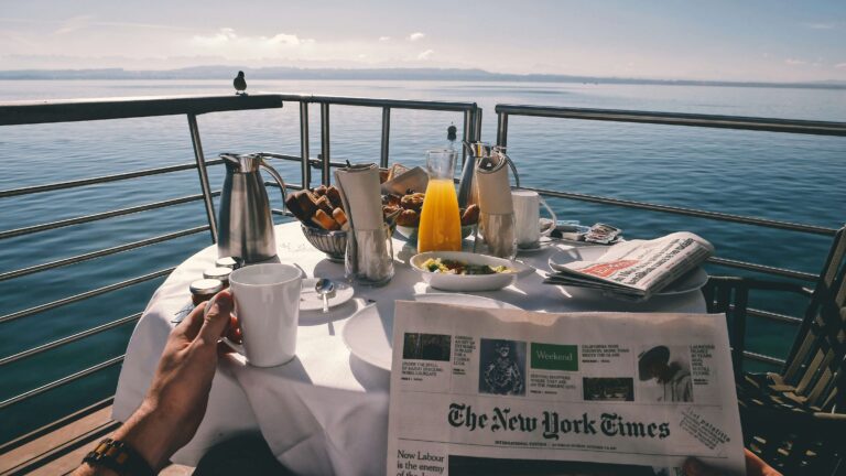 A breakfast table all set up outside on a cruise ship overlooking the sea.