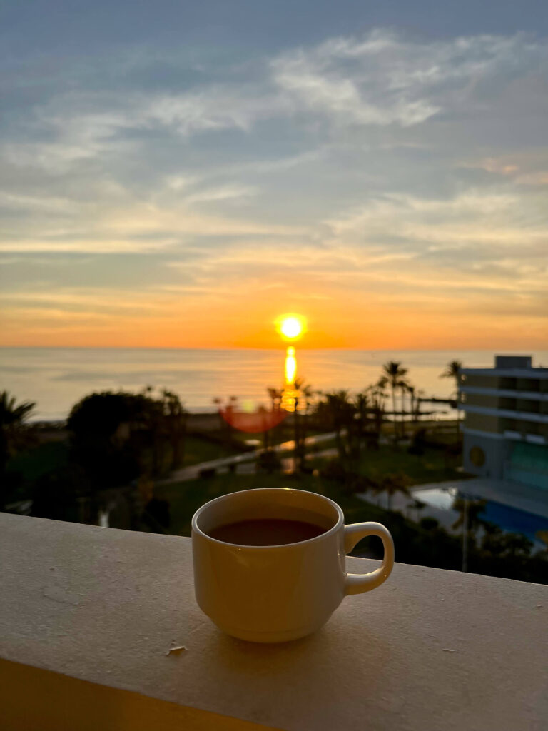 A coffee cup rests on the balcony during sunset in Paphos.