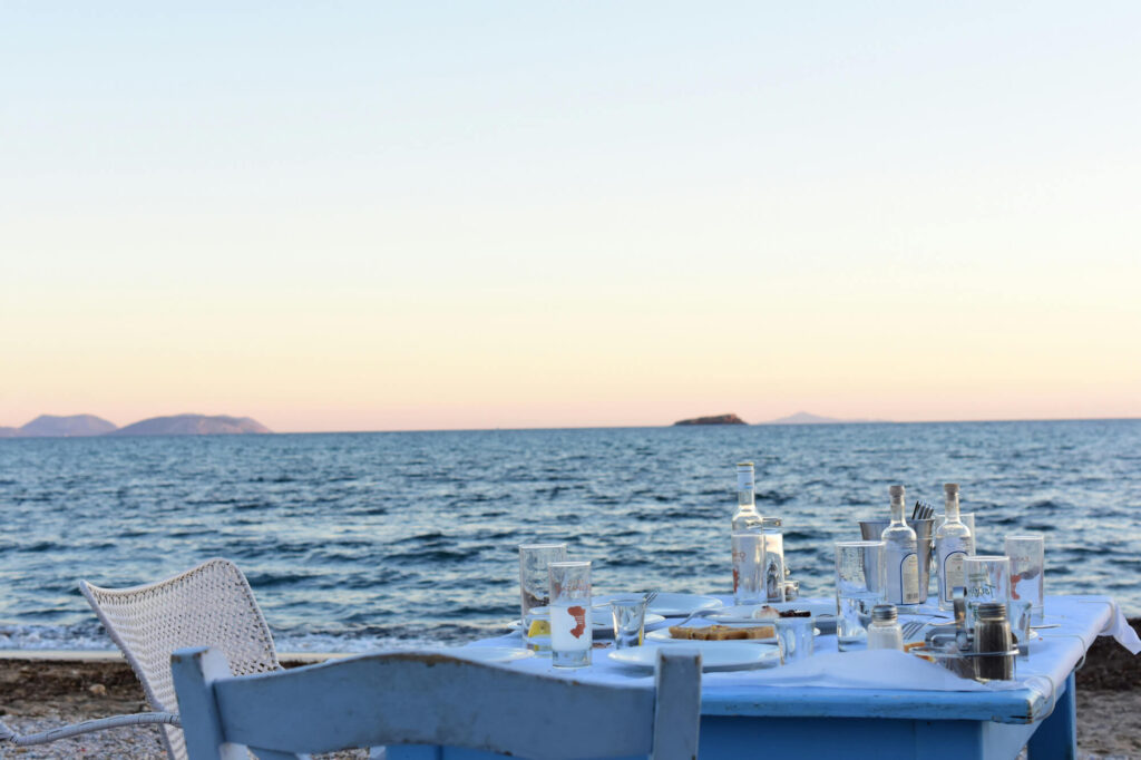 A table set with ouzo by the sea in Greece.