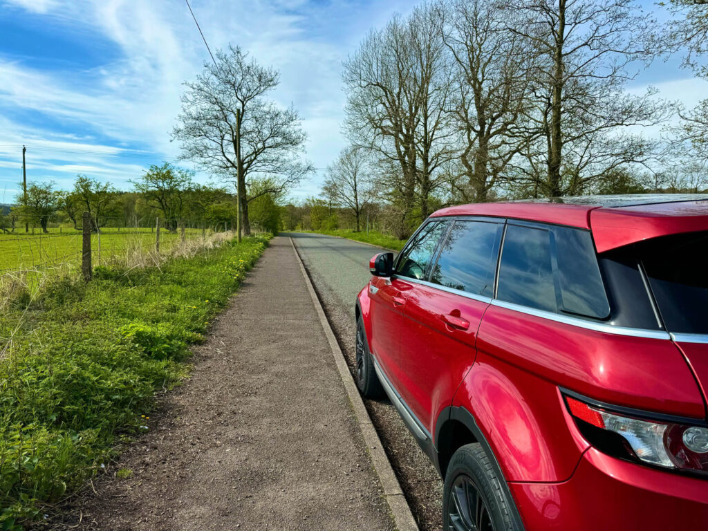 A red Range Rover Evoque parked on a country lane.