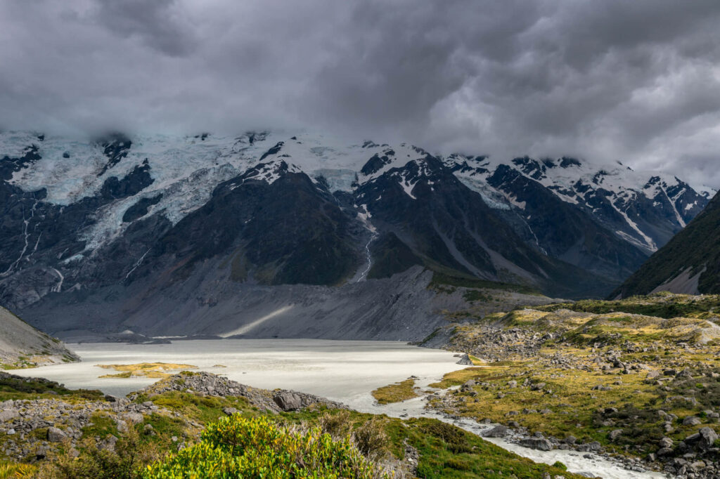 Snow-capped mountains tower above a lake in Peel Forest, New Zealand.