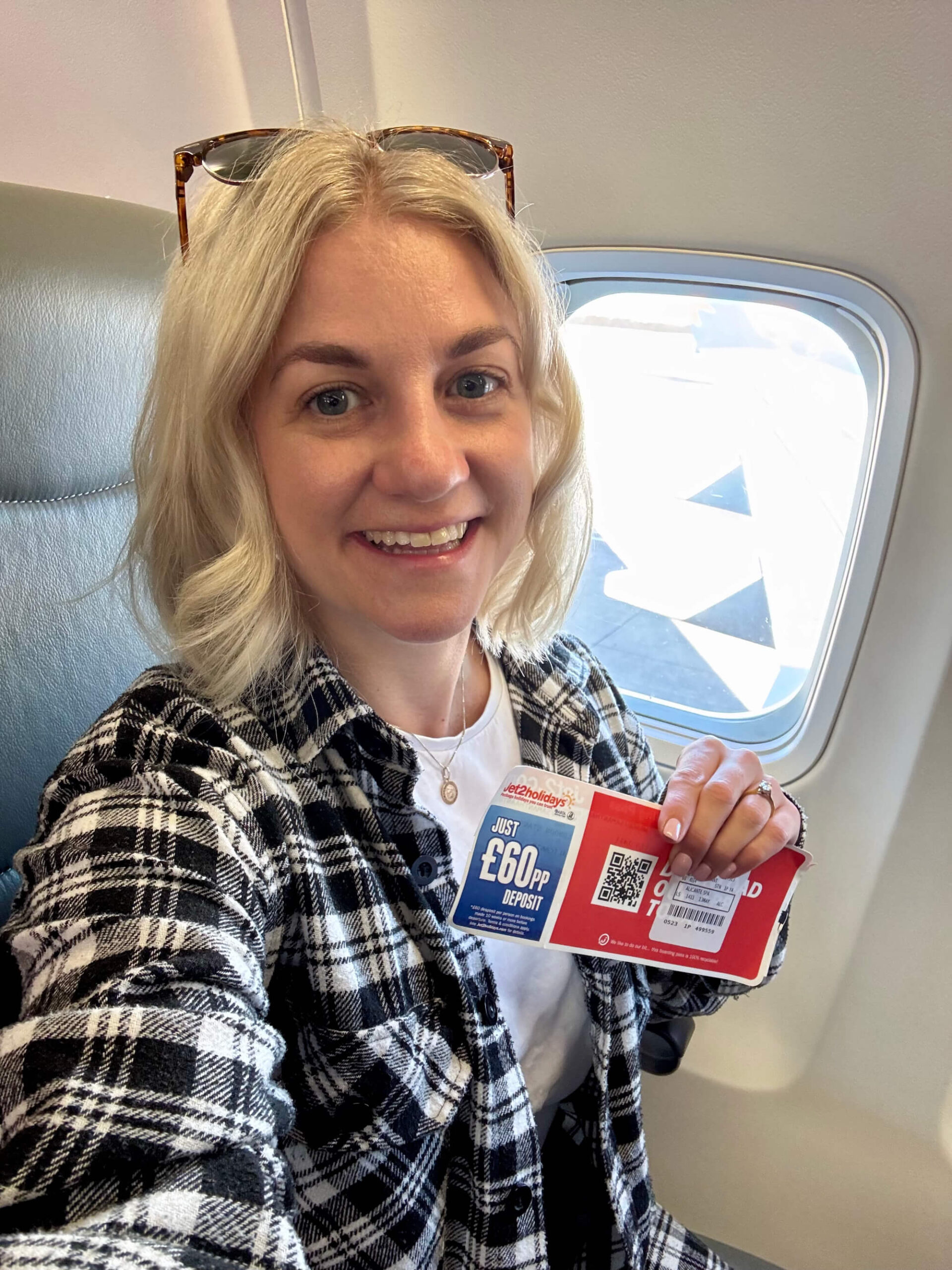 Sam sat on a plane holding a Jet2 boarding pass.