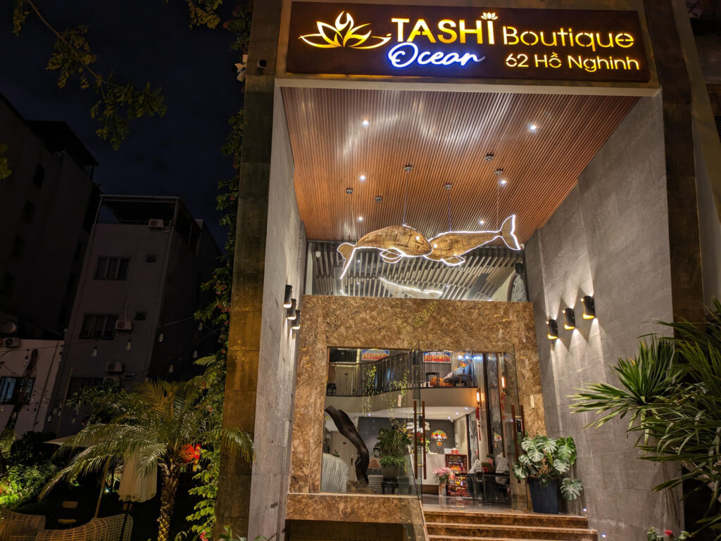 The entrance to Tashi Hotel & Apartment lit up at night.
