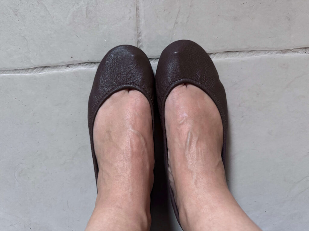 The Tieks ballet flats in chocolate being worn.
