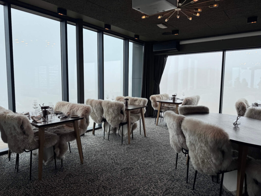 The interior of Skyskraperen Restaurant with floor to ceiling windows and sheepskin-style blankets.