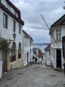 A view down a pretty street in Bergen between wooden buildings down to the sea.